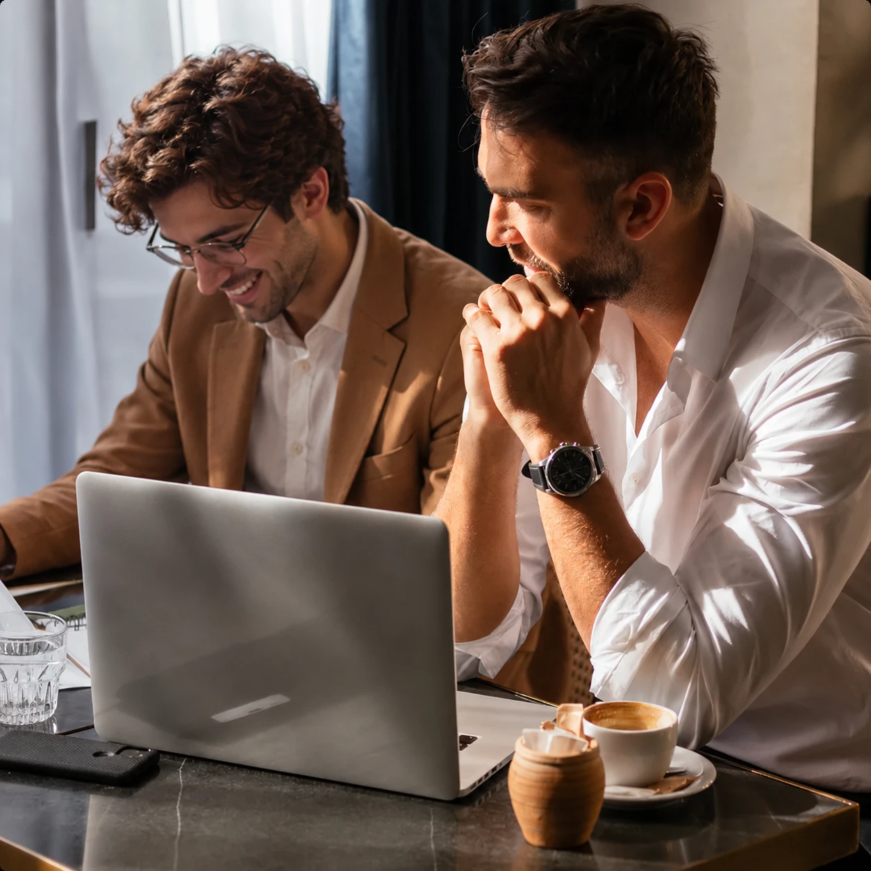 Two colleagues reviewing work on a laptop